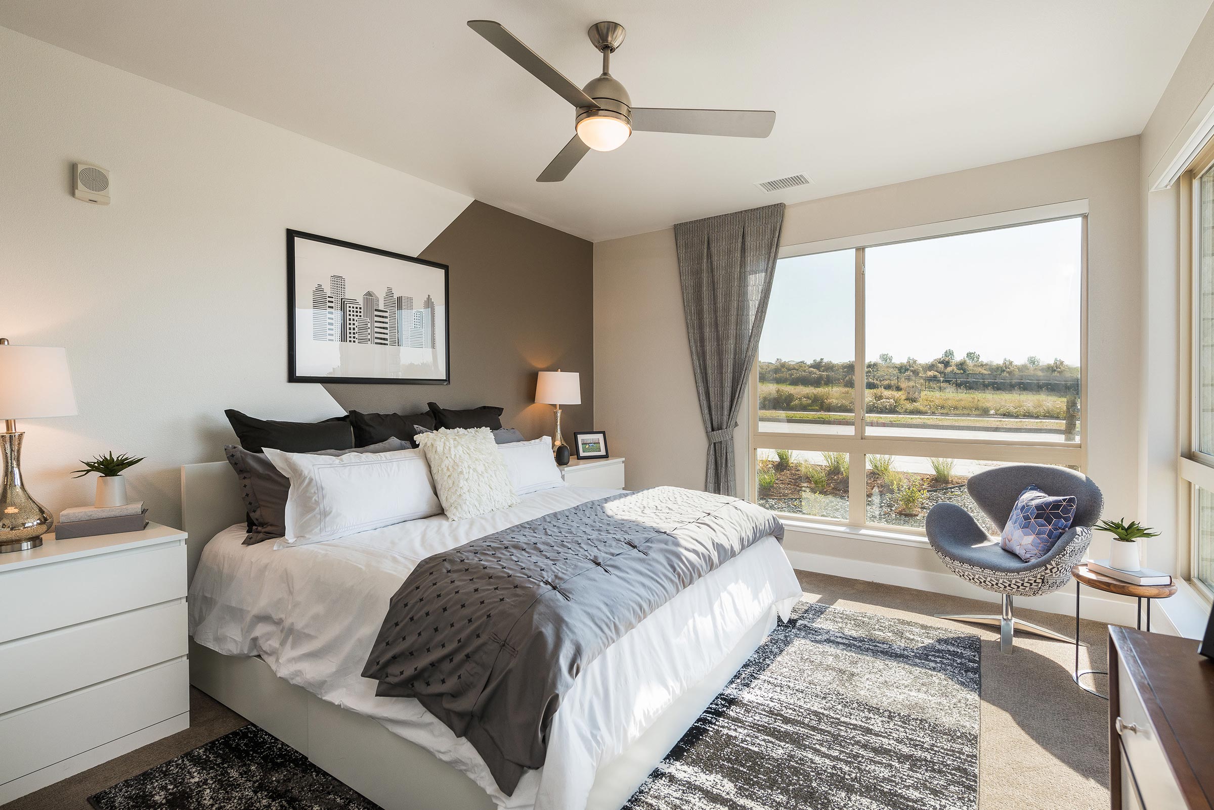 A modern bedroom in Solana Central Park with abstract black-and-white artwork above the bed, soft lighting, and an ensuite bathroom visible through an open door.