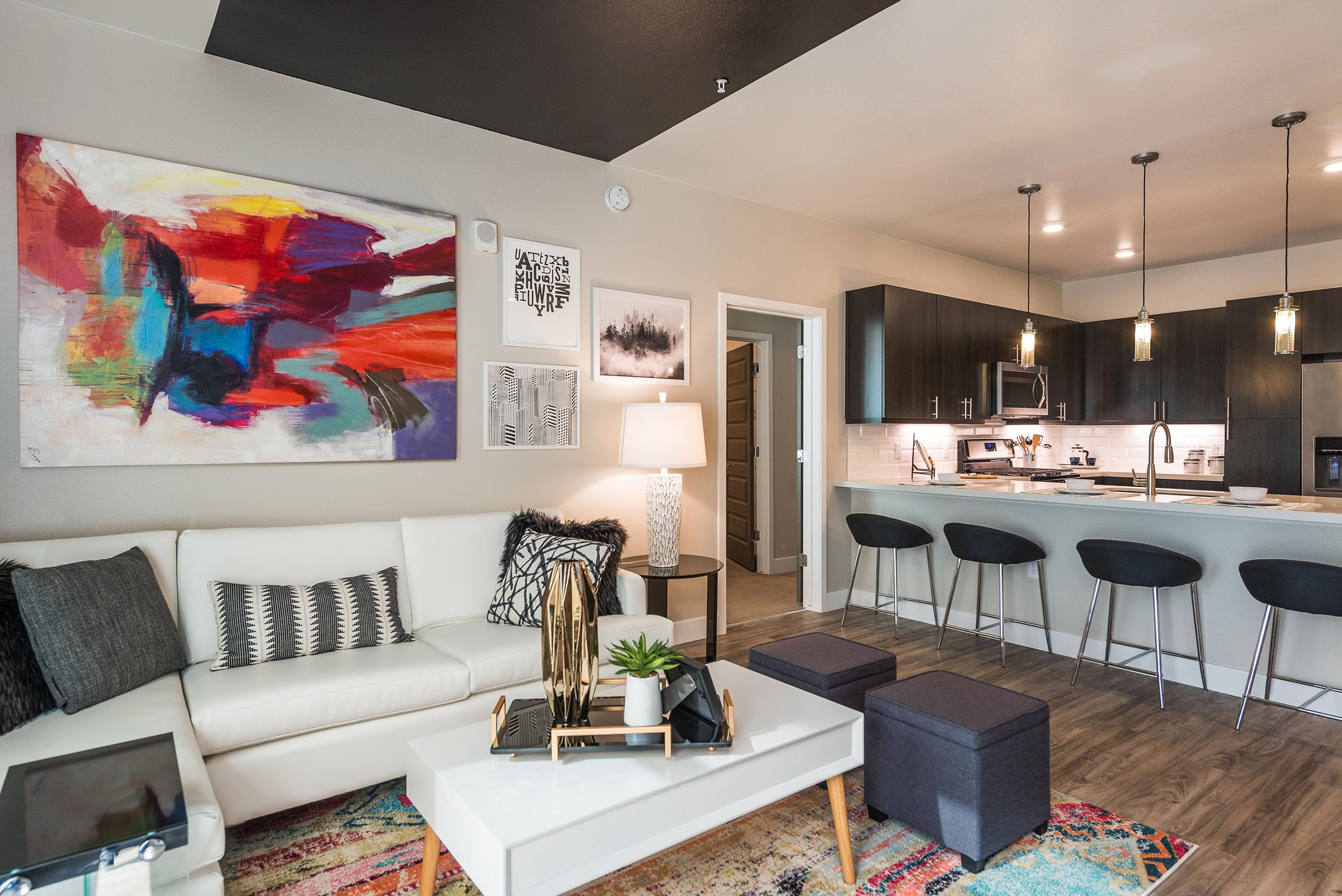 A modern lounge space in Solana Central Park featuring a communal table, wooden high chairs, pendant lighting, and decorative shelving with two large TV screens mounted on the wall.